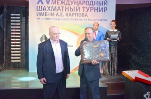 Руководитель Ханты-Мансийского регионального отделения Российского союза промышленников и предпринимателей Александр Кобанов вручает сладкий подарок организаторам турнира. Огромный пряник передали из Тулы, именно там родился Анатолий Карпов, чьё имя теперь носит международный шахматный турнир